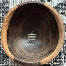 Load image into Gallery viewer, NKYINKYIM A sterling silver Adinkra symbol charm displayed in a wooden bowl. The charm has geometric patterns representing perseverance.
